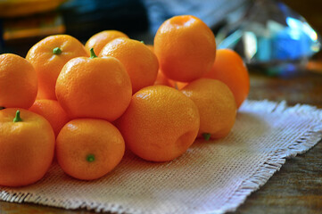 Ripe tangerines lie on a pink napkin on the table. The ripening season of tropical citrus fruits....