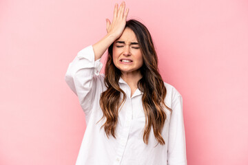 Young caucasian woman isolated on pink background forgetting something, slapping forehead with palm and closing eyes.