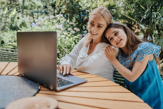 Mother and daughter on video call through laptop at back yard