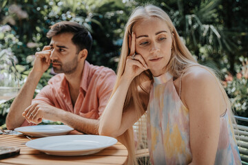Couple ignoring each other at outdoor table