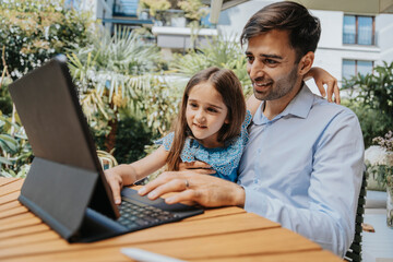 Smiling father and daughter using tablet computer at yard