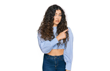 Young hispanic girl wearing casual clothes pointing aside worried and nervous with forefinger, concerned and surprised expression