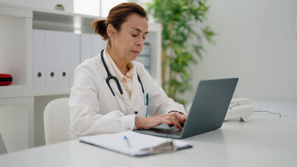 Fototapeta na wymiar Middle age hispanic woman wearing doctor uniform working at clinic