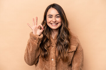Young caucasian woman isolated on beige background cheerful and confident showing ok gesture.