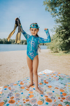 Girl holding diving flippers at lakeshore on weekend
