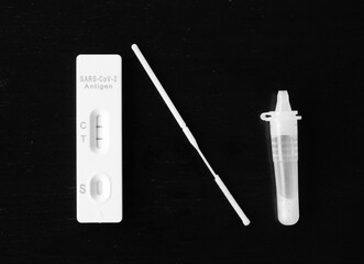 Selective focus picture of covid-19 test kit showing positif result using nasal swab on dark wood...