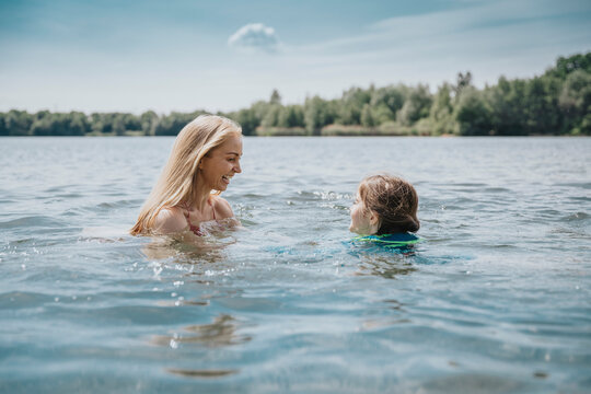 Happy mother and daughter swimming in lake