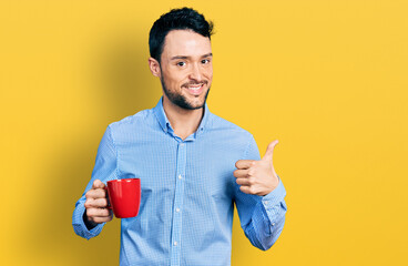 Hispanic man with beard drinking a cup coffee smiling happy and positive, thumb up doing excellent and approval sign