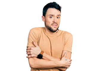 Fototapeta premium Hispanic man with beard wearing casual t shirt shaking and freezing for winter cold with sad and shock expression on face