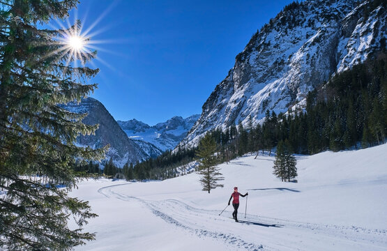 Active senior woman skiing in snow by mountains
