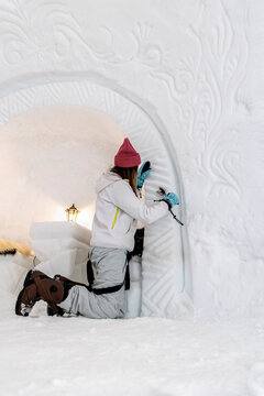 Woman carving design on wall in igloo