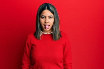 Fototapeta premium Young latin woman wearing casual clothes sticking tongue out happy with funny expression. emotion concept.