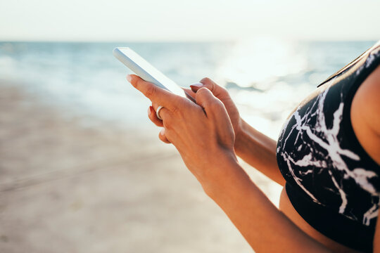 Woman in sports bra using smart phone at beach