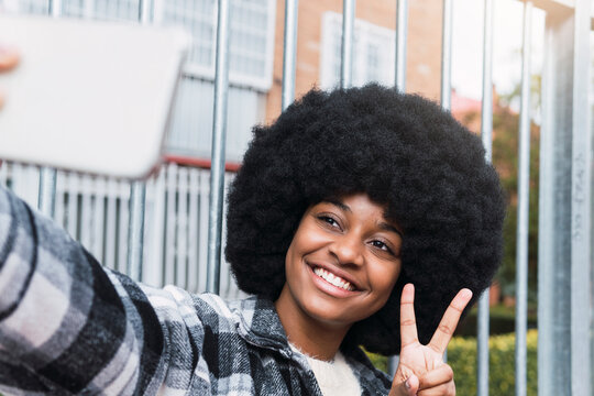 Happy woman taking selfie showing peace sign - Powered by Adobe