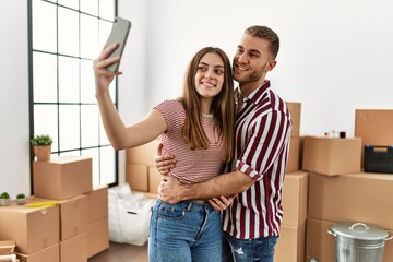 Fototapeta na wymiar Young caucasian couple smiling happy make selfie by the smartphone at new home.