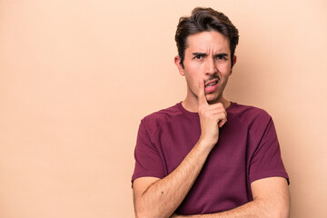 Young caucasian man isolated on beige background looking sideways with doubtful and skeptical expression.