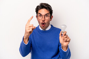 Young caucasian man holding a lightbulb isolated on white background having an idea, inspiration concept.