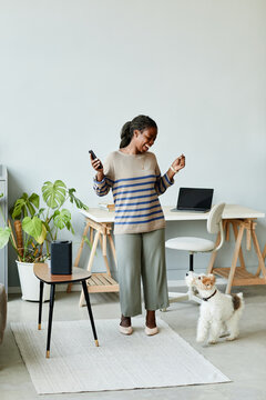 Full Length Portrait Of Young African American Woman Dancing To Music At Home Using Smart Speaker With AI Technology