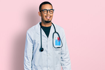 Young african american man wearing doctor uniform and stethoscope winking looking at the camera...