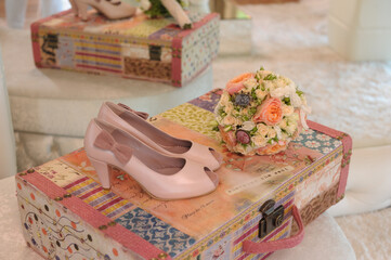 Beautiful bridal bouquet and bride shoes over a suitcase. Wedding shoes and wedding bouquet of roses.