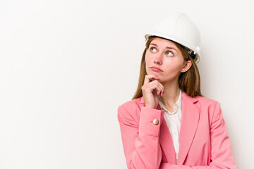 Young architect English woman with helmet isolated on white background looking sideways with doubtful and skeptical expression.