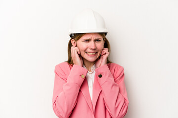 Young architect English woman with helmet isolated on white background covering ears with hands.