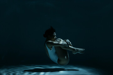 Woman in fetal position swimming underwater