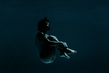 Young woman in fetal position swimming underwater