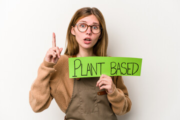 Young gardener woman holding a plan based placard isolated on white background having an idea, inspiration concept.