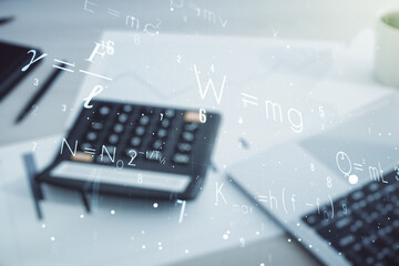 Abstract scientific formula hologram on calculator and laptop background. Multiexposure