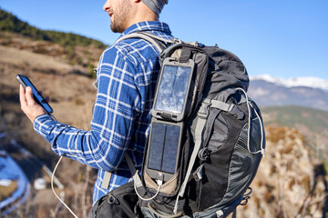 Man wearing backpack with portable solar panel on sunny day
