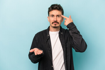 Young caucasian man isolated on blue background holding and showing a product on hand.