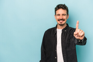 Young caucasian man isolated on blue background showing number one with finger.
