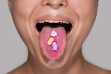 Half of female face with colorful pills on tongue. - obrazy, fototapety, plakaty