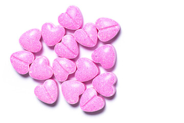 Closeup shot of pink heart shaped pills on white background.