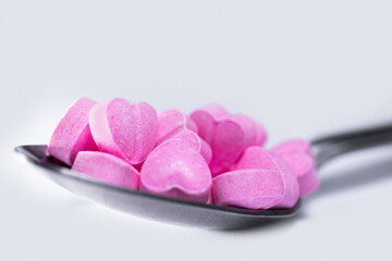 Closeup shot of spoon filled with heart shaped pills.