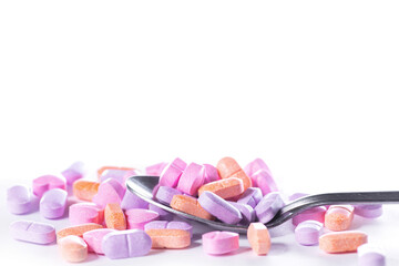 Closeup shot of spoon and pile of pills on white background.