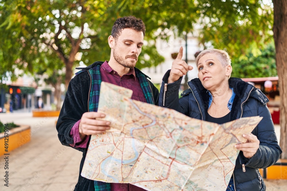 Wall mural mother and son looking city map standing together at park