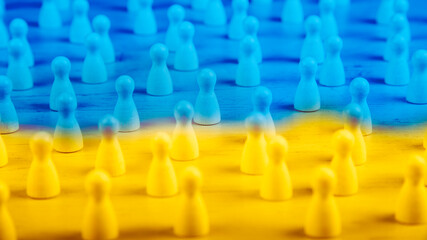Obraz premium wooden figurines in blue and yellow as symbol for people in ukraine and refugees