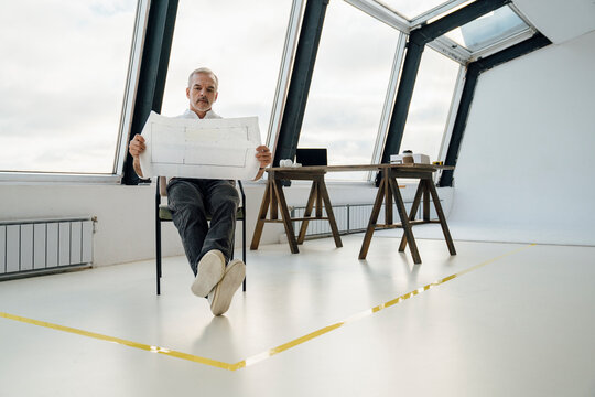 Businessman examining paper document sitting at work place