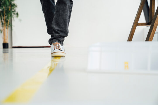 Businessman walking on yellow striped marking at startup office