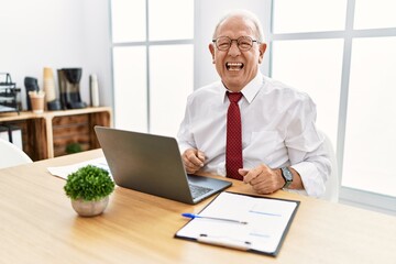 Senior man working at the office using computer laptop angry and mad screaming frustrated and furious, shouting with anger. rage and aggressive concept.