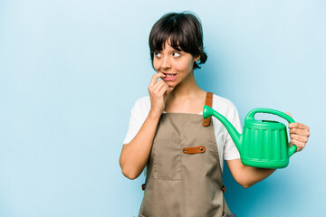 Young hispanic gardener woman holding a watering can isolated on blue background relaxed thinking about something looking at a copy space.