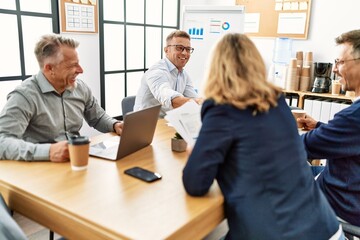 Group of middle age business workers smiling and looking partners handshake at the office.
