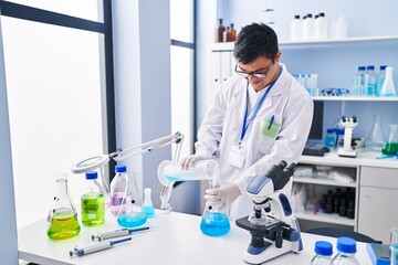 Down syndrome man wearing scientist uniform pouring liquid on test tube at laboratory