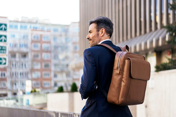 Businessman with backpack walking in city