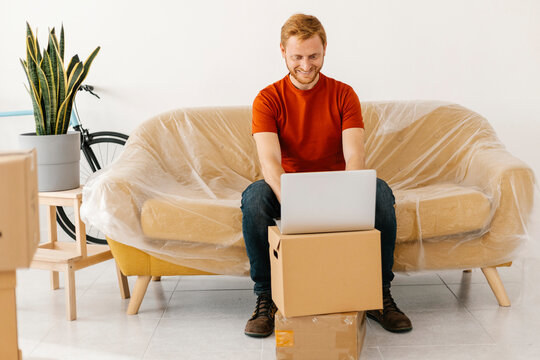 Happy Man Using Laptop Sitting On Sofa At Home