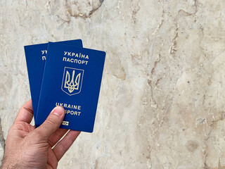 Turkey, Antalya, March 7, 2022 - A man's hand holds 2 foreign passports of refugees on a marble...