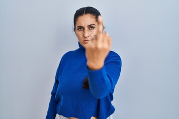 Young hispanic woman standing over isolated background showing middle finger, impolite and rude...