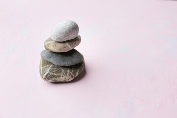 Three white stones for meditation, therapy and yoga on the pink background